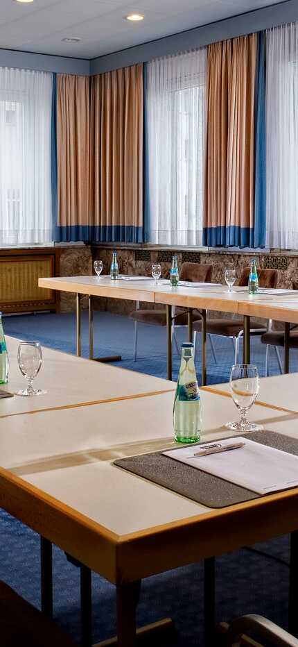 A well-organized conference room with arranged chairs and tables, prepared for a meeting with notepads and water bottles.