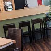 A stylish hotel bar features sleek wooden stools and a modern countertop, accentuated by a decorative plant.