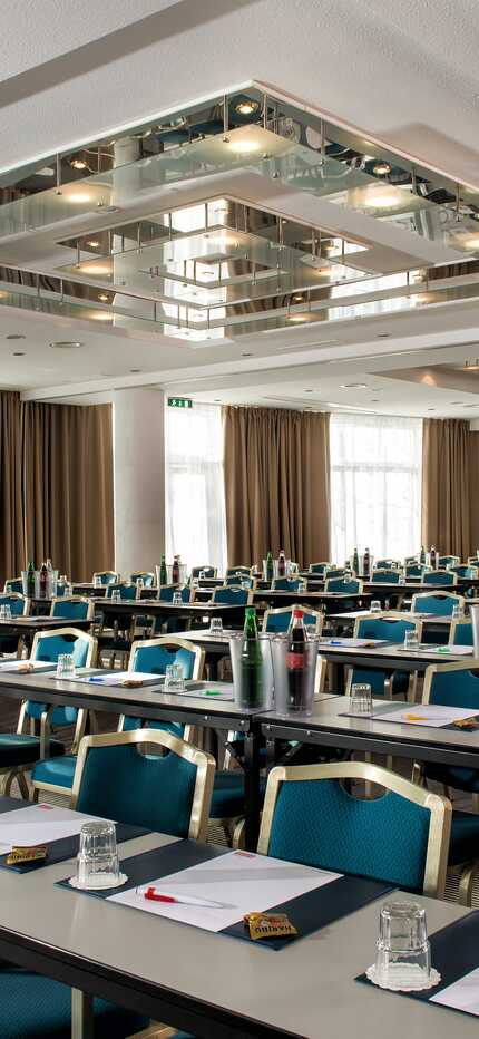 Ein geräumiger Konferenzraum mit Reihen von Tischen und Stühlen, bereit für ein Meeting im Goethe-Saal.