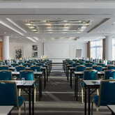 Ein moderner Meetingraum mit blauen Stühlen und gedeckten Tischen ist bereit für eine Konferenz im Goethe-Saal.