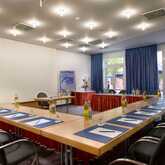 A spacious meeting room with a U-shaped table setup, featuring blue notepads and bottled water for attendees.