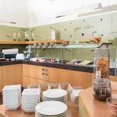 A well-stocked breakfast buffet in a restaurant features cereals, fresh fruits, and beverages, inviting guests to enjoy a morning meal.