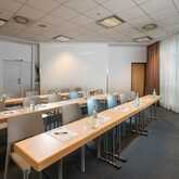 A conference room setup with tables, chairs, and bottled water, featuring a large smiling face poster on the wall.