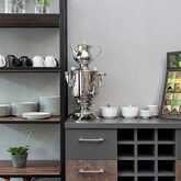 A breakfast setup features a samovar, neatly stacked plates, mugs, and a colorful tea selection on shelves.