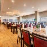 Ein elegantes Restaurant mit gedeckten Tischen und roten Stühlen lädt zu einem entspannten Abendessen ein.
