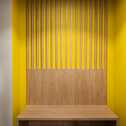 A modern family room features a vibrant yellow wall with wooden slats and a bench, creating a warm, inviting atmosphere.