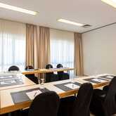 A bright meeting room in Kampenwand features arranged tables with notepads and glasses, ready for a conference.