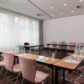 A modern meeting room is set up with tables, chairs, and notepads, ready for a conference or business gathering.