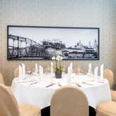 Ein eleganter, runder Esstisch ist für ein Essen gedeckt, mit einem Schwarz-Weiß-Bild von Salzburg an der Wand.