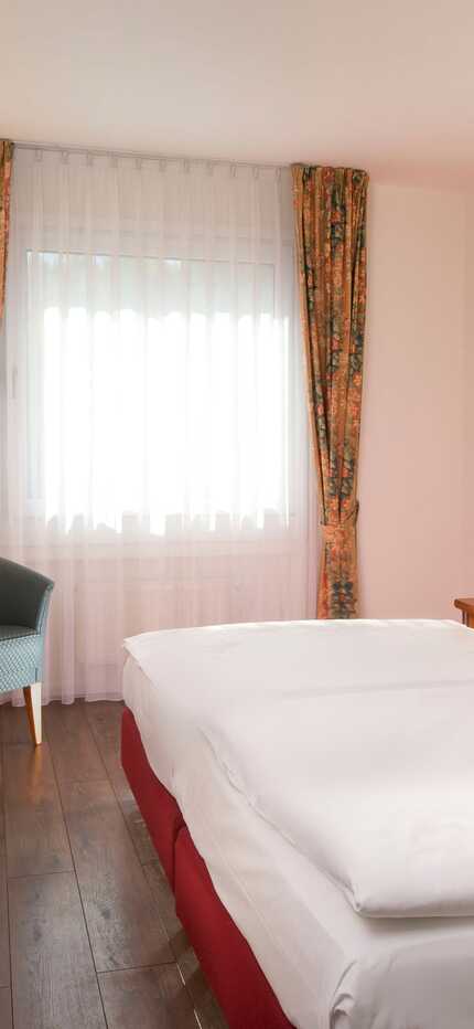 Ein gemütliches Doppelzimmer mit einem großen Bett, einem Schreibtisch, einem Fernseher und geschmackvoller Einrichtung.