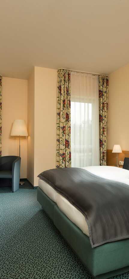 A spacious double room features a large bed, modern decor, and comfortable seating, perfect for a relaxing stay at the Residenz.