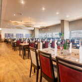 Ein elegantes Restaurant mit gedeckten Tischen und roten Stühlen lädt zu einem entspannten Abendessen ein.