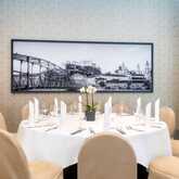 Ein eleganter, runder Esstisch ist für ein Essen gedeckt, mit einem Schwarz-Weiß-Bild von Salzburg an der Wand.