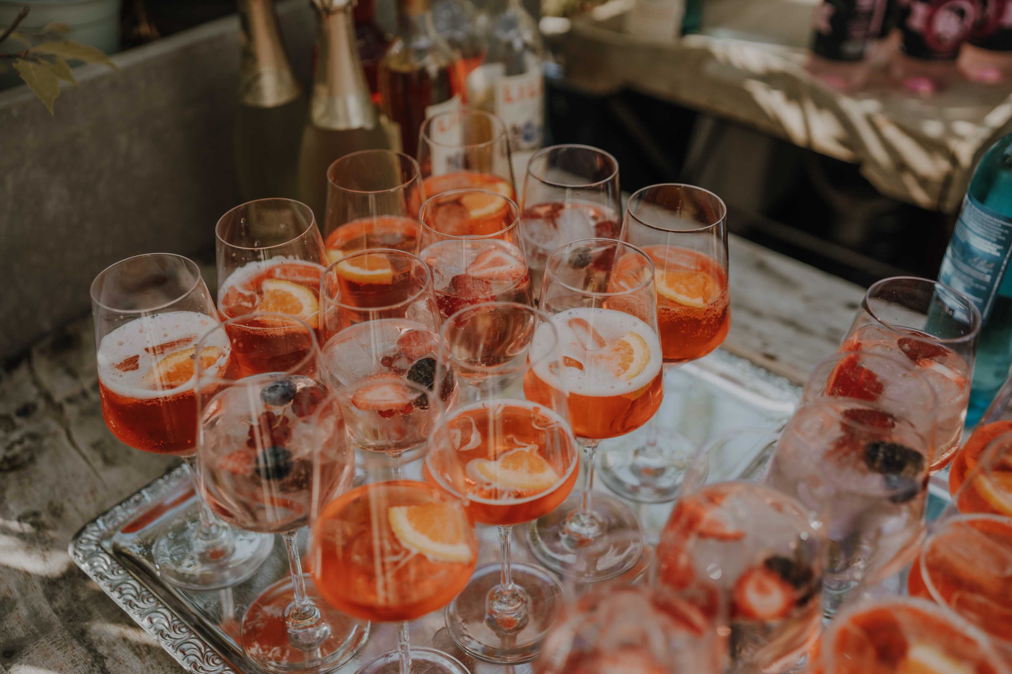 Ein Tablett voller spritziger Getränke mit Orangen- und Beerenstücken sorgt für sommerliche Erfrischung.