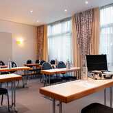 A conference room set for a meeting with tables, chairs, bottled water, and a briefcase open on one table.