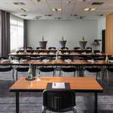 A conference room is set up with neatly arranged tables, chairs, and bottled water, ready for a meeting or seminar.