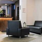 A modern hotel lobby features sleek black sofas and a warmly lit reception desk adorned with elegant decor.