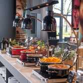 A vibrant breakfast buffet in a restaurant features eggs, cereals, and colorful dishes under sleek warming lamps.