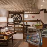 A cozy restaurant interior features a buffet table with drinks and food, accented by warm lighting and rustic decor elements.
