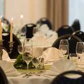 Elegant banquet room with candlelit tables, neatly folded napkins, and sparkling glassware set for a sophisticated event.
