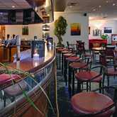 Elegante Hotelbar mit geschwungener Theke, zahlreichen Flaschen und gemütlichen Sitzmöglichkeiten lädt zum Verweilen ein.