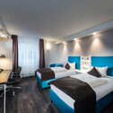 Moderner Twin-Bed-Raum mit zwei Betten, Schreibtisch und HDTV in stilvollem Design.