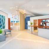 A serene wellness spa lobby features a large succulent artwork, wicker chairs, and a calming Buddha statue on the counter.