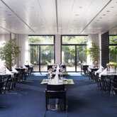 A modern restaurant with elegant table settings and large windows overlooking a lush garden.