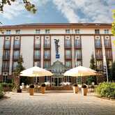 The front view of a grand hotel features large windows, a welcoming entrance, and two large umbrellas in the courtyard.