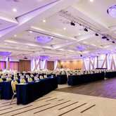 A spacious conference room with elegant lighting and neatly arranged tables and chairs, ready for a high-profile event.