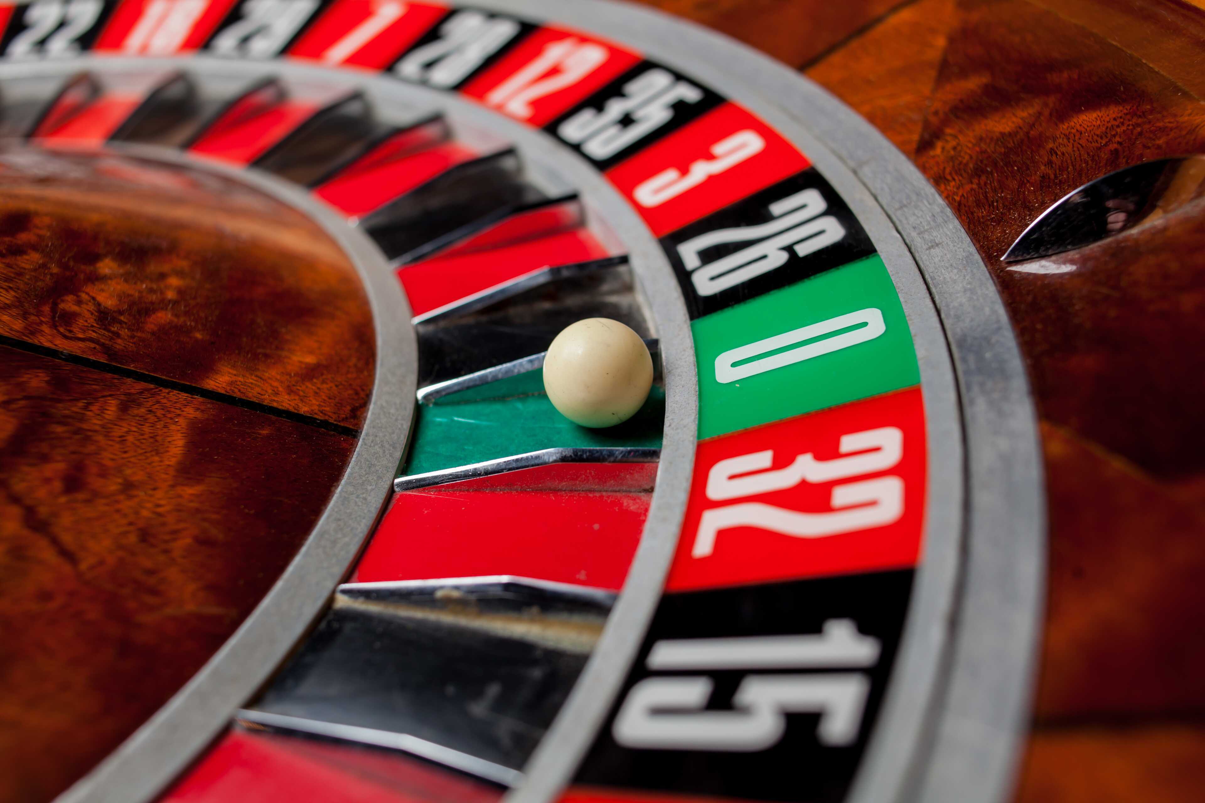 Eine Roulettekugel landet auf der grünen Null auf einem hölzernen Roulettetisch und signalisiert Spannung im Casino.
