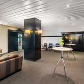 Eine moderne Lobby mit gemütlichen Sitzgelegenheiten, Stehtischen und einem Buffet mit Getränken und Snacks.