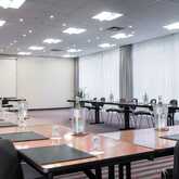 A modern conference room with a U-shaped table setup, ready for a meeting with notepads and water bottles.