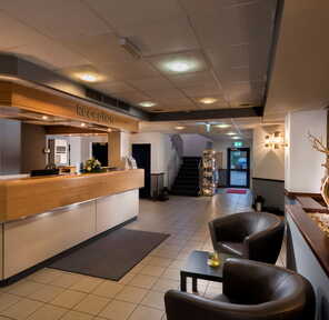 Modern hotel lobby featuring a reception desk, cozy seating, and stylish decor in a welcoming atmosphere.