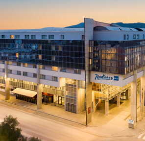Das Radisson Blu-Hotel präsentiert sich modern mit großen Fenstern und einem klaren Design am Abend. | © Radisson