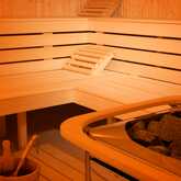 A warm, inviting sauna features wooden benches and a bucket with a ladle, perfect for a relaxing experience.