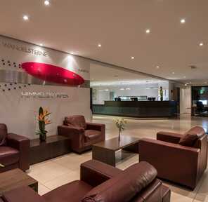 A modern lobby features leather chairs, artistic wall decor, and a sleek reception desk, creating a welcoming atmosphere.