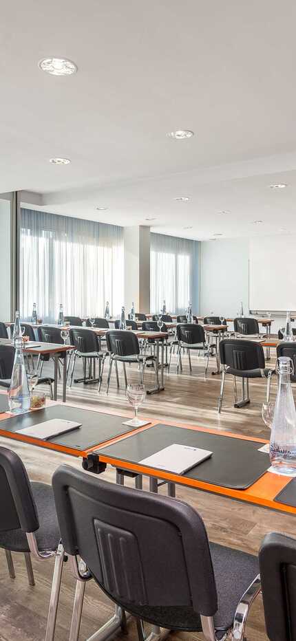A well-lit classroom at Wittenberg School is set for a seminar with neatly arranged tables, chairs, and bottled water.