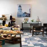 An inviting buffet table is set with a variety of pastries, snacks, and drinks for a coffee break in a modern room.