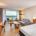 Ein stilvolles Hotelzimmer mit modernem Interieur, einem Schreibtisch und einem Balkon mit Blick auf die Landschaft.
