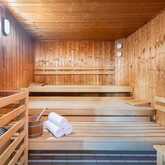 Eine leere Sauna mit Holzbänken, einem Eimer und Handtüchern lädt zur Entspannung ein.