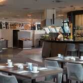 Der Frühstücksbereich im Hotel zeigt gedeckte Tische und einen Koch an der Bar, bereit für die Gäste.