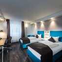Explore the comfortable twin room at Best Western Hotel Cologne Airport Troisdorf, perfect for travelers preferring separate beds. The room offers two cozy single beds and a stylish blue armchair for added relaxation.