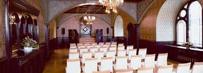 The Rittersaal features elegant arched windows, chandeliers, and rows of white chairs arranged for an event.
